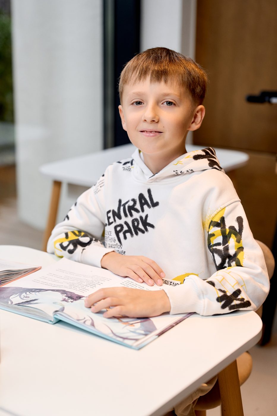 Усміхнений хлопчик за столом з відкритою книжкою